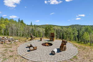 View of patio with a wooded view and an outdoor fire pit
