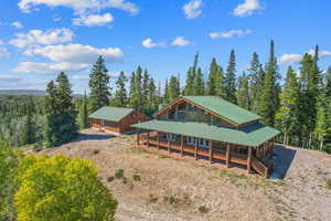 Rear view of property featuring covered porch, a wooded view, and metal roof