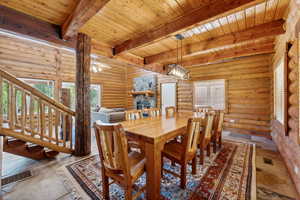 Dining space featuring wooden ceiling, a fireplace, beamed ceiling, and log walls