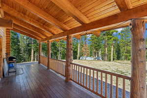 Wooden deck with view of wooded area and area for grilling