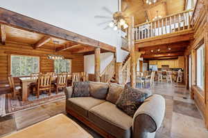 Living area with a chandelier, beamed ceiling, wood ceiling, rustic walls, and stairs