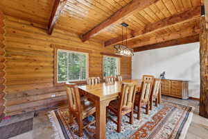 Dining room with wood ceiling, beam ceiling, log walls, and a chandelier