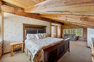 Bedroom featuring beamed ceiling, light colored carpet, wood ceiling, and wood walls
