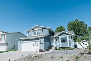 View of front facade with board and batten siding, concrete driveway, an attached garage, fence, and brick siding