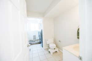 Bathroom with toilet, tile patterned floors, baseboards, and vanity