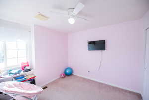 Exercise area with carpet flooring, baseboards, and a ceiling fan