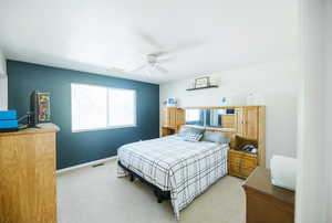 Bedroom featuring light carpet, a ceiling fan, and baseboards
