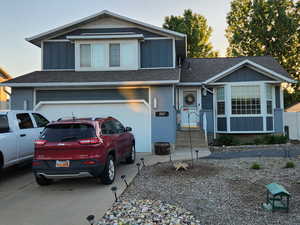 View of front facade featuring board and batten siding, a garage, driveway, roof with shingles, and entry steps