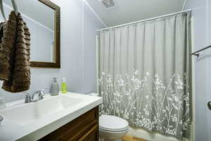 Bathroom featuring toilet, vanity, and shower / bath combo with shower curtain