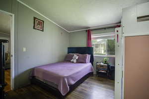 Bedroom with wood finished floors and crown molding