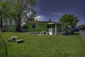 Rear view of house featuring a storage unit, an outdoor structure, a chimney, and a porch