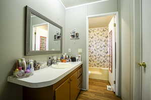 Bathroom with wood finished floors, vanity, toilet, and shower / bathtub combination with curtain