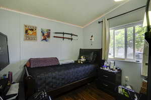 Bedroom with crown molding and dark wood finished floors