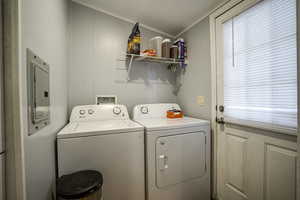 Clothes washing area featuring washing machine and clothes dryer, electric panel, and ornamental molding