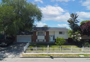 Raised ranch with driveway, brick siding, and a garage