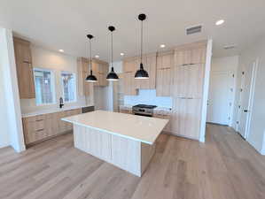 Kitchen with light brown cabinets, light quartz countertops, modern cabinets, a center island, and recessed lighting