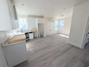 ADU-Kitchen featuring white cabinets, light wood-type flooring, butcher block countertops, modern cabinets, and an AC wall unit