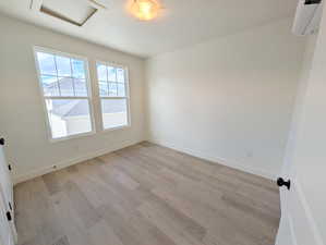 ADU-Bedroom with an AC wall unit, light wood finished floors, and attic access