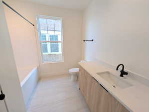 Full bath with vanity, light tile patterned floors, and shower / washtub combination