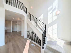 Staircase featuring wood finished floors, a high ceiling, metal railing, and recessed lighting