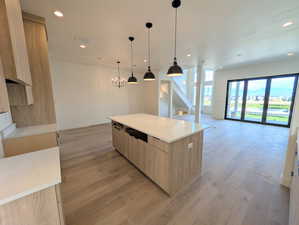 Kitchen featuring light brown cabinetry, open floor plan, recessed lighting, light wood finished floors, and light stone countertops