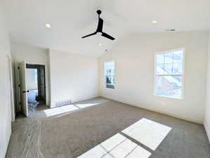 Primary bedroom featuring carpet flooring, multiple windows, recessed lighting, ceiling fan, and lofted ceiling