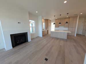 Kitchen with light wood-type flooring, open floor plan, recessed lighting, pendant lighting, and light brown cabinetry