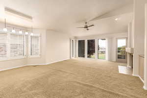 Carpeted spare room featuring ceiling fan, baseboards, vaulted ceiling, and a textured ceiling