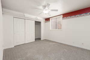 Unfurnished bedroom with a closet, carpet floors, a textured ceiling, a ceiling fan, and baseboards