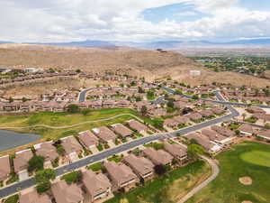 Aerial view of property and surrounding area with nearby suburban area, a golf club, and a water and mountain view