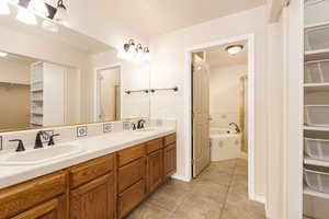 Bathroom with tile patterned floors, a walk in closet, double vanity, and a bathtub