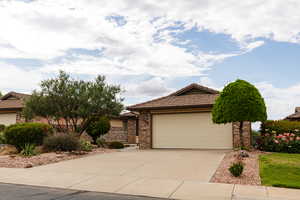 Single story home with a tile roof, concrete driveway, brick siding, and a garage