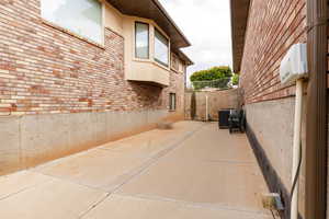 View of side of home with cooling unit, brick siding, a patio area, fence, and stucco siding