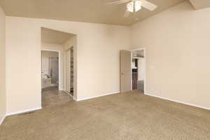 Unfurnished room featuring carpet floors, ceiling fan, baseboards, and vaulted ceiling
