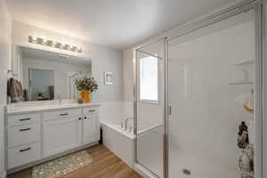 Bathroom with a stall shower, wood finished floors, vanity, and a garden tub