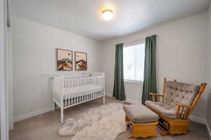 Bedroom with baseboards, a crib, and carpet