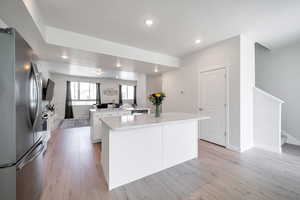Kitchen with appliances with stainless steel finishes, a center island, light wood-style flooring, white cabinets, and recessed lighting