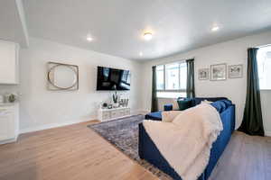 Living room featuring light wood-type flooring, baseboards, recessed lighting, and a textured ceiling