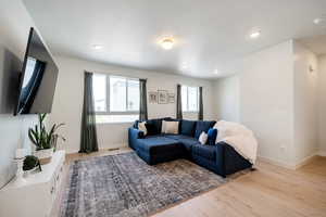 Living area with light wood-style floors, baseboards, and recessed lighting