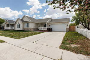 Ranch-style house with brick siding, an attached garage, driveway, and a porch