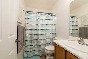 Bathroom featuring toilet, vanity, and a shower with curtain