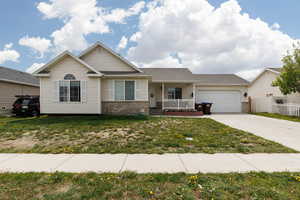 Ranch-style house featuring brick siding, a garage, covered porch, and concrete driveway