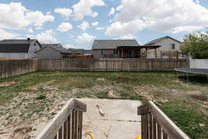 Fenced backyard featuring a trampoline