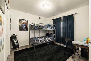 Bedroom with wood finished floors, baseboards, and a textured ceiling
