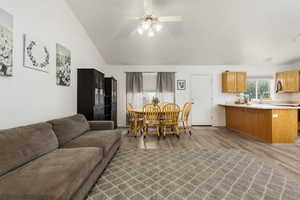 Living area with vaulted ceiling, light wood-style floors, and a ceiling fan