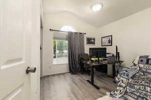 Home office featuring wood finished floors, lofted ceiling, and a textured ceiling