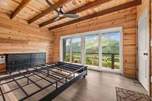 Bedroom featuring wooden ceiling, wooden walls, beam ceiling, multiple windows, and hardwood / wood-style floors