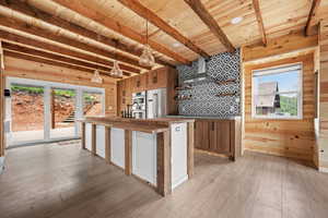 Kitchen featuring appliances with stainless steel finishes, wooden ceiling, light wood finished floors, wall chimney range hood, and beamed ceiling