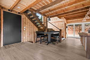 Interior space with stairs, wood walls, wooden ceiling, beamed ceiling, and wood finished floors