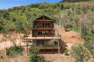 Back of property with a balcony and a view of trees